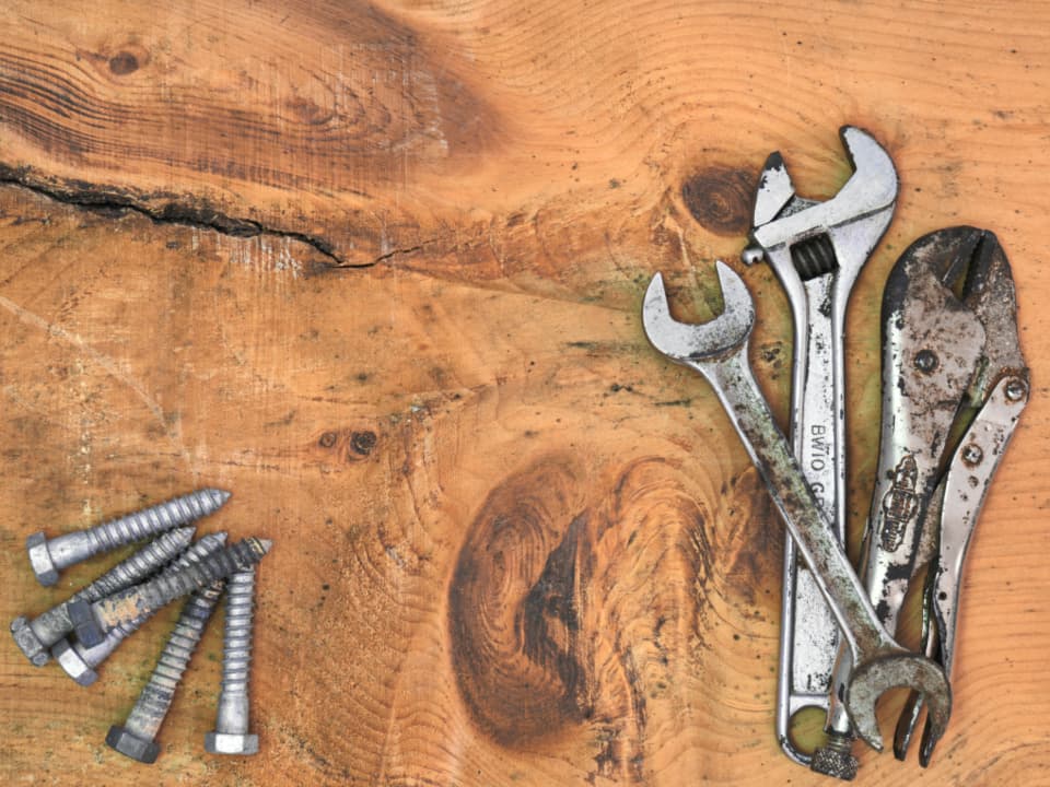 Wrenches and bolts laid out on a wooden workbench