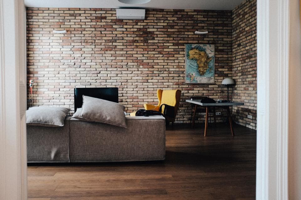 A living room with an exposed brick wall and grey sofa