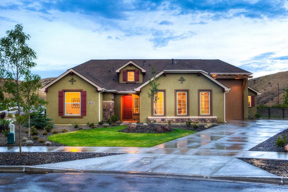 A single-storey house with a lawn and a wet driveway