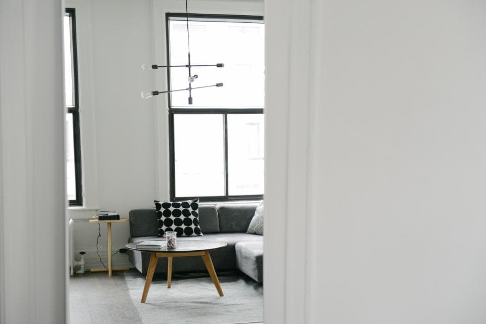 A white corner living room with a grey sofa and black pendant lamp
