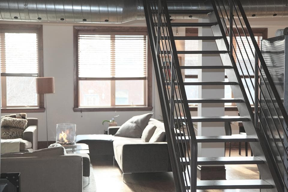An open-plan loft living room with a black metal staircase