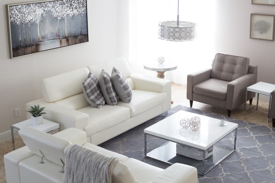 A bright living room with a white sofa, armchair and rug