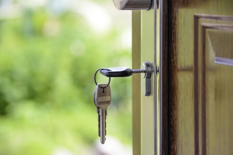 A set of keys hanging from the lock of an open door
